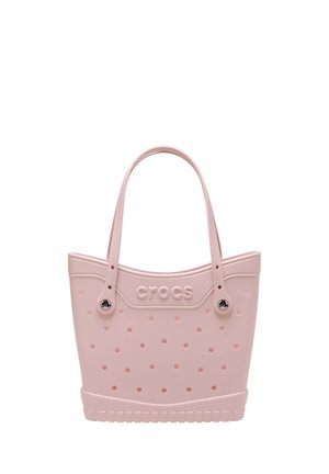 Hellrosa Crocs Tragetasche mit mehreren Belüftungslöchern, zwei Griffen und Logo, das in der Mitte vorne eingeprägt ist.