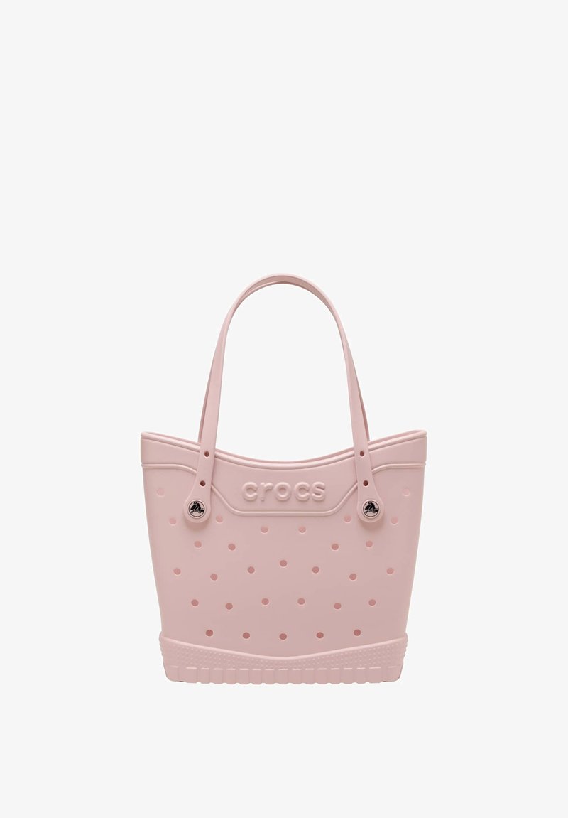 Jasnoróżowa torba typu tote marki Crocs z licznymi otworami wentylacyjnymi, dwoma uchwytami i logo wytłoczonym na środku przodu.