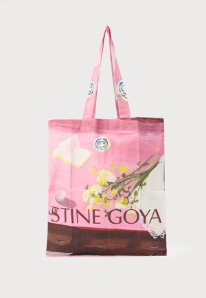 Rosa stoffveske med blomster- og borddekkingsmotiv, med gule blomster, tallerkener og teksten "STINE GOYA" nederst.