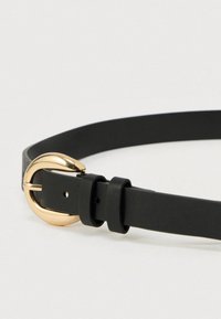 Μαύρη δερμάτινη ζώνη με στρογγυλή αγκράφα σε χρυσό τόνο, λεία υφή και ρυθμιζόμενο μέγεθος με πολλαπλές τρύπες για διαφορετικές διαστάσεις.