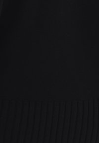 Schwarzer Strickstoff mit glatter Textur, der am unteren Rand einen gerippten Saum aufweist. Die Gesamtform ist figurbetont und minimalistisch gestaltet.