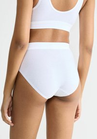 Weißer nahtloser Slip mit hohem Bund, aus weicher Baumwolle. Bietet eine glatte Textur und ein schlichtes Design, ohne sichtbare Muster oder Akzente.