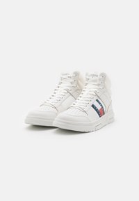 Sneakers bianchi alte in pelle, con punta rotonda, dettagli perforati e una striscia laterale multicolore con blu navy, rosso e bianco.