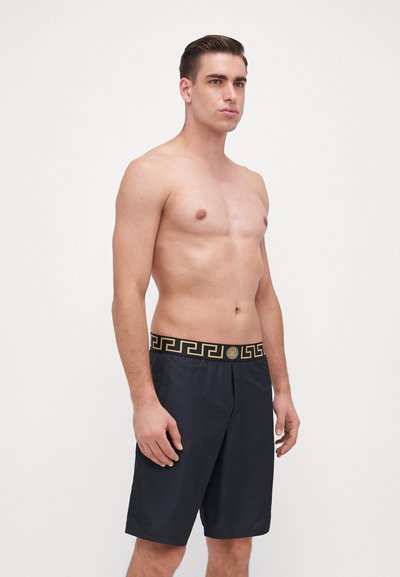 Calções de banho pretos com uma cintura em padrão dourado contrastante. Feitos de um tecido suave, apresentando um corte relaxado e um design até ao joelho.