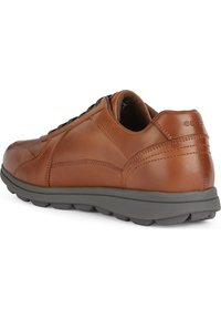Sneaker in pelle marrone con punta rotonda, suola in gomma grigia e dettagli di cucitura. I lacci garantiscono una vestibilità sicura; logo visibile sul tallone.