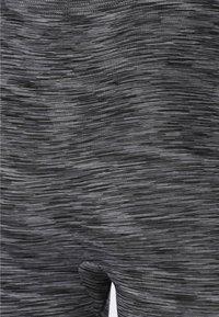 Mustat ja harmaat kuviolliset legginsit, joissa on teksturoitu pinta, sisältäen yhdistelmän pystysuoria ja vaakasuoria raitoja sekä keskikorkean vyötärön.