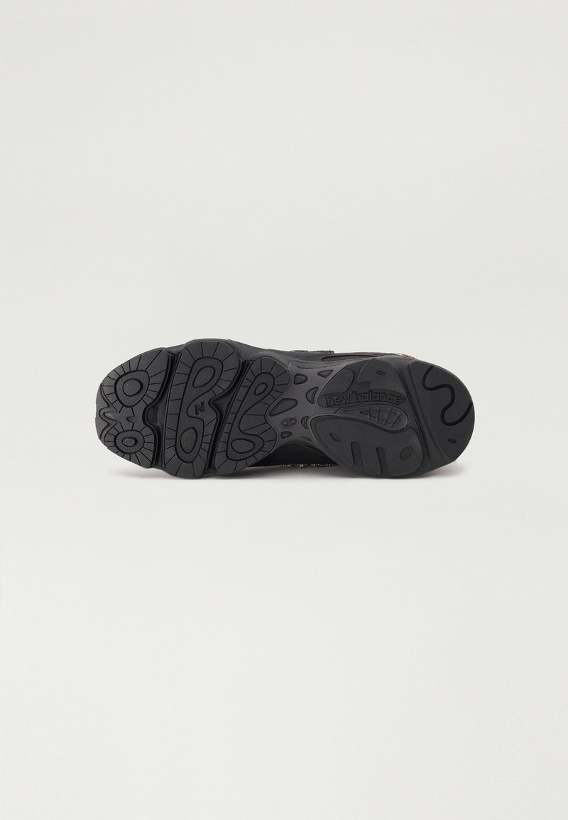 Semelle de chaussure de sport noire avec motif en caoutchouc texturé, motifs arrondis et logo de la marque. Conçue pour l'adhérence et la durabilité.