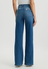 Hoch taillierte, weit geschnittene blaue Denim-Jeans mit einem leicht ausgewaschenen Finish. Verfügt über zwei Gesäßtaschen und einen gesteppten Saum.
