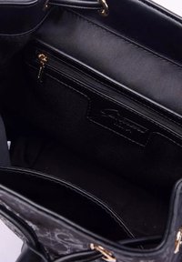 Interno di una borsa nera con rivestimento in tessuto liscio, una tasca con cerniera e un'etichetta di marca ben visibile. Il design presenta scomparti e dettagli di cucitura.