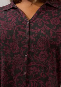 Koszula zapinana na guziki w czarnym kolorze z bordowym wzorem kwiatowym, o prążkowanej fakturze, z kołnierzykiem i wieloma guzikami z przodu.