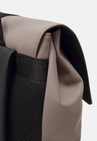 Sac gris et noir doté d'un dessus lisse en caoutchouc avec un design roulé, de côtés en mesh et de détails de couture robustes.