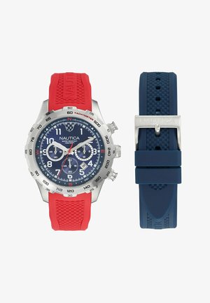 Orologio cronografo Nautica con cassa in acciaio inossidabile color argento, quadrante blu navy, cinturino in silicone rosso con texture, include un cinturino aggiuntivo blu.