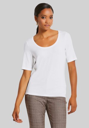 Witte T-shirt met korte mouwen en een ronde halslijn, gemaakt van een gladde stof. Gecombineerd met bruine geruite, op maat gemaakte broeken.
