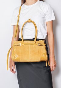 Borsa a mano in suede giallo con dettagli in pelle liscia, doppi manici superiori e una tracolla removibile. Presenta cuciture decorative e una forma rettangolare.