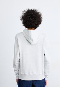 Gray hoodie in soft material with a drawstring hood, ribbed cuffs, and hem, viewed from the back. Features a smooth texture and minimal design.