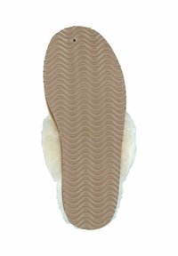 White fuzzy slipper with a textured beige rubber sole featuring a wavy pattern, showing soft fur lining along the edge.