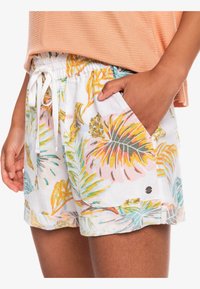 Shorts légers avec un fond blanc orné de motifs de feuilles tropicales colorées. Taille élastique avec cordon de serrage ; poches latérales visibles.
