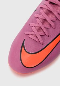 Lilla fotballsko med teksturert overflate, med rosa snøring og en markant oransje Nike-logo med svart omriss.