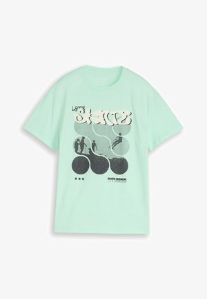 T-shirt vert menthe avec le texte « Let's Skate » et des silhouettes noires de personnes en train de faire du skateboard à l’intérieur de formes circulaires. Texte « Skate Session Ongoing » en dessous.