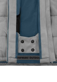 Grau gepolsterte Jacke mit blauem Akzent, Reißverschluss vorne und großer Innentasche mit vier schwarzen Druckknöpfen. Innen sichtbarer Text.