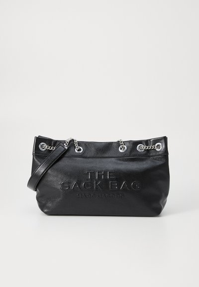 Sac à main en cuir noir avec une texture douce, présentant des accents de chaîne en argent, un texte en relief et un design spacieux. Crochets pour une bandoulière réglable.