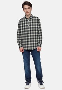 Knap-op skjorte med et sort og hvidt ternet mønster, lavet af letvægtsstof, parret med blå jeans og hvide sneakers.