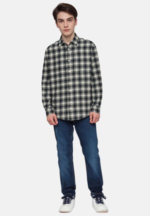 Overhemd met knoopsluiting met een zwart-wit geruit patroon, gemaakt van lichtgewicht stof, gecombineerd met blauwe jeans en witte sneakers.