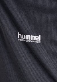 Czarna koszulka sportowa wykonana z teksturowanego materiału, z białym logo "hummel PERFORMANCE" z przodu.