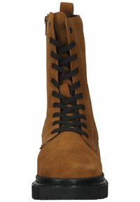 Botte à lacets en daim marron avec une tige haute, des lacets noirs et une semelle en caoutchouc noire robuste avec une finition texturée.