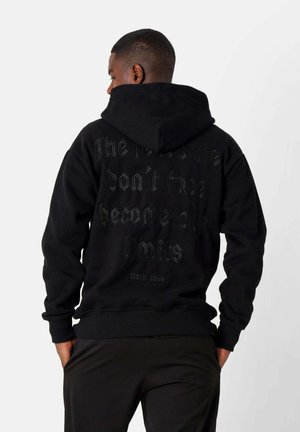 Zwarte hoodie met een trekkoord in de capuchon. Kenmerkt zich door reliëftekst op de achterkant in een contrasterende donkere kleur. Ribbelige manchetten en zoom. Soepele textuur.