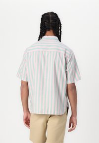 Chemise à manches courtes avec des boutons, présentant des rayures verticales en rose clair et vert menthe, fabriquée en tissu de coton léger.