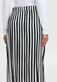 Langes Kleid mit vertikalen navy- und weißen Streifen, aus einem weichen Stoff gefertigt, mit einer taillierten Taille und dezenten Nahtdetails an der Seite.