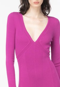 Šaty s dlouhým rukávem a výstřihem do V v elastickém žebrovaném vzoru, v živé magentové barvě, s obepínajícím siluetou a diagonálním švem.