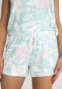 Blommiga shorts i ljusblått, med vita och rosa mönster. Gjorda av mjukt tyg, med resår i midjan och dragsko.