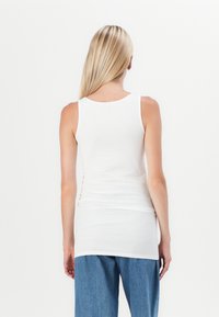 Witte tanktop van zachte stof, met een ronde hals en zonder mouwen, gecombineerd met losse blauwe spijkerbroek.