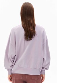 Sweatshirt lavande avec des manches surdimensionnées, des poignets et un ourlet côtelés. Texture douce, design minimal et coupe légèrement courte.