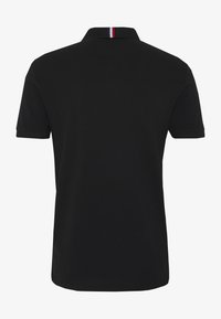 Polo noir à manches courtes, avec une couleur unie et un col rayé en rouge, blanc et bleu.