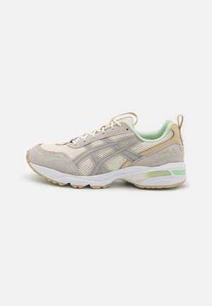 Let beige og mintgrøn atletiksneaker med netstof, ruskind detaljer, polstret sål og trækstrop på hælen, sidevisning.