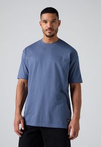 Herre kortærmet t-shirt i ensfarvet blå bomuld, med rund halsudskæring, der har et lille logo på brystet og et mærke i kanten.
