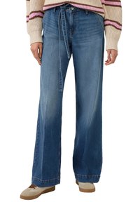 Jeansy o szerokich nogawkach, w średnim odcieniu niebieskiego, wykonane z denimu. Posiadają wysoki stan i materiałowy pasek do wiązania. Wykończone prostym dołem.