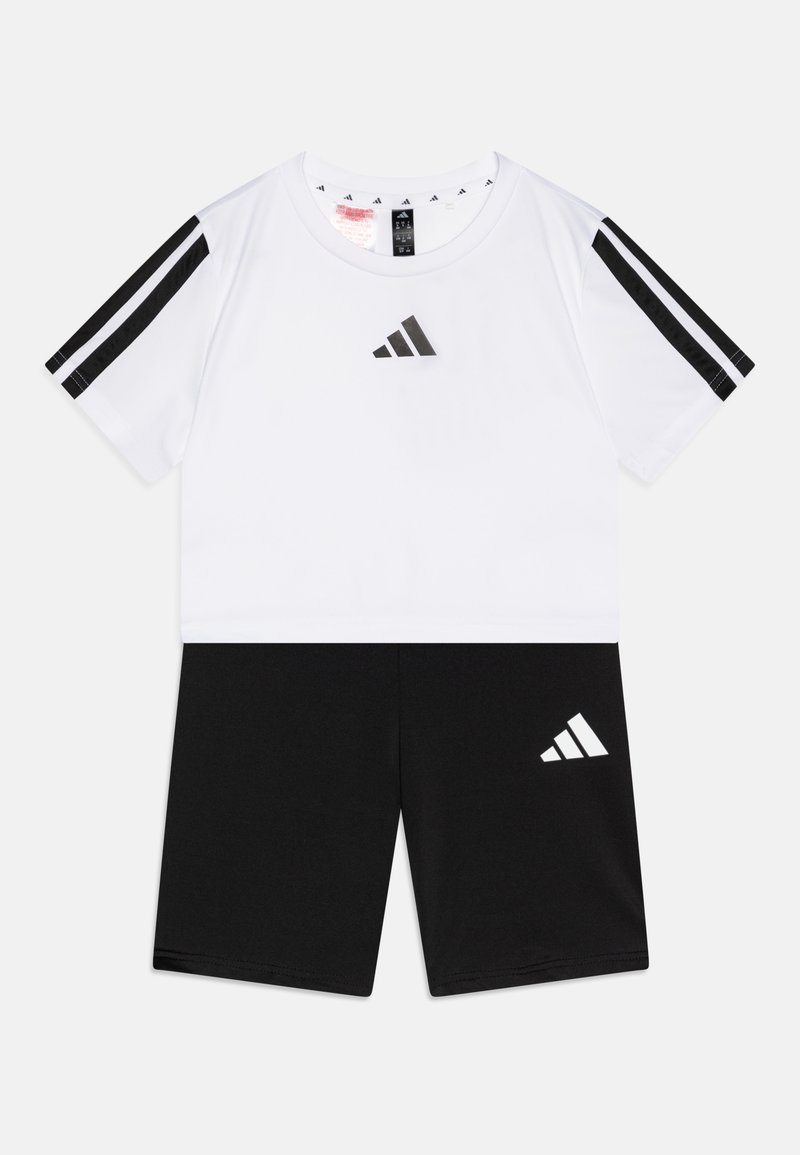 Conjunto deportivo de Adidas que incluye una camiseta blanca de manga corta con detalles y logotipo en negro, acompañada de un pantalón corto negro que presenta un logotipo blanco.