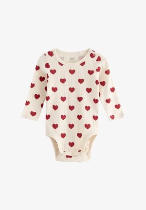 Cremefarvet langærmet heldragt med et struktureret mønster af røde hjerter. Har trykknapper ved skulderen og bunden for nem påklædning.