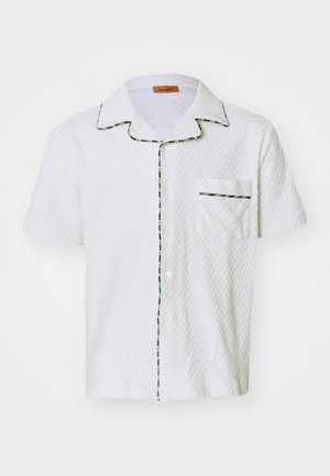 Chemise blanche à manches courtes avec texture en chevrons, passepoil noir et bord multicolore le long du col et de la poche. Poche poitrine unique.