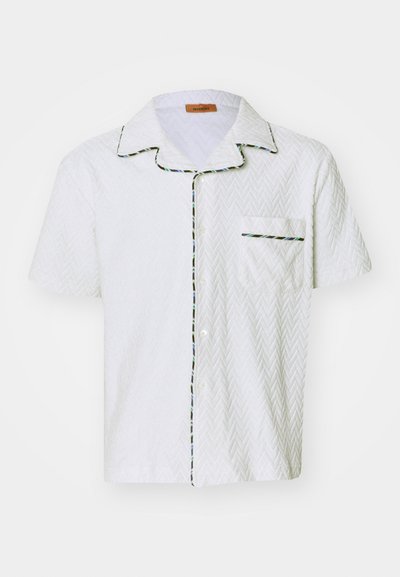 Camisa branca de manga curta com textura de espinha de peixe, detalhes em preto e acabamento multicolorido ao longo do colarinho e do bolso. Bolso de peito único.