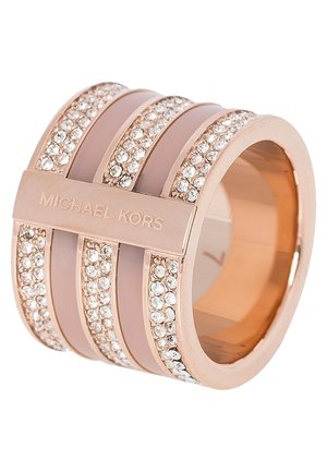 Szeroka różowo-złota obrączka z wieloma rzędami przejrzystych kryształków i wygrawerowanym napisem "MICHAEL KORS" na centralnym poziomym pasku.