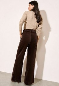 Bruine corduroy wijde broek met een hoge taille, textuur-ribbels en voorzakken, gecombineerd met een beige aansluitend lang mouwtop.