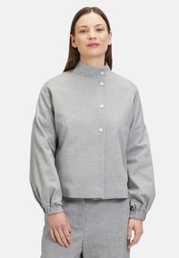 Grijs button-up jas met een hoge kraag, voorzien van lange, gepofte mouwen en een gestructureerde stof. Inclusief zilveren knopen aan de voorkant.