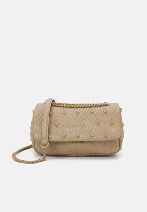 Sac à main en cuir matelassé beige avec une chaîne, présentant un motif en diamants et un logo à l'avant. Forme compacte et rectangulaire.