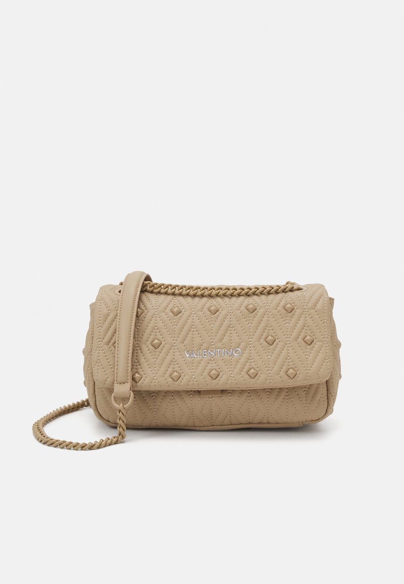 Sac à main en cuir matelassé beige avec une chaîne, présentant un motif en diamants et un logo à l'avant. Forme compacte et rectangulaire.