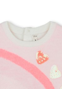 Pull en tricot rose clair avec un col rond, doté d'une bordure blanche et de trois cœurs en sequins rouges et blancs.